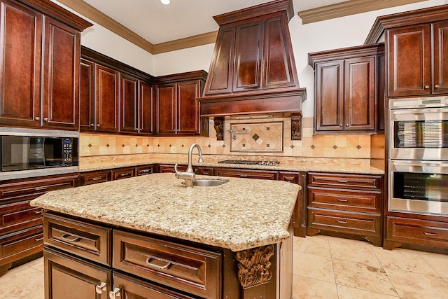 kitchen featuring appliances with stainless steel finishes, backsplash, custom exhaust hood, sink, and a center island with sink