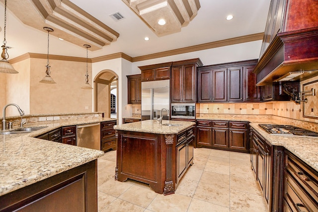 kitchen featuring pendant lighting, built in appliances, light stone counters, and sink