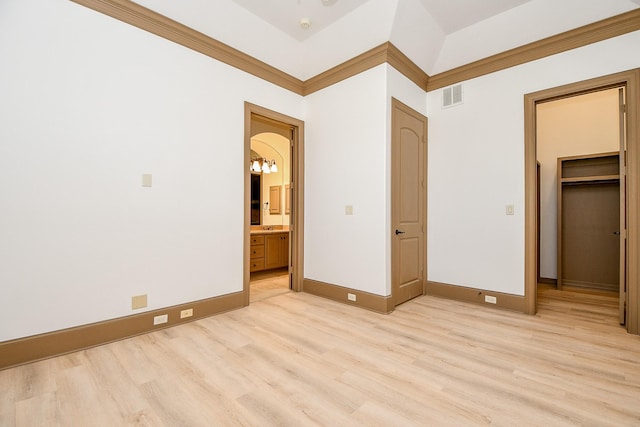 unfurnished bedroom with a closet, a walk in closet, ensuite bathroom, and light hardwood / wood-style flooring