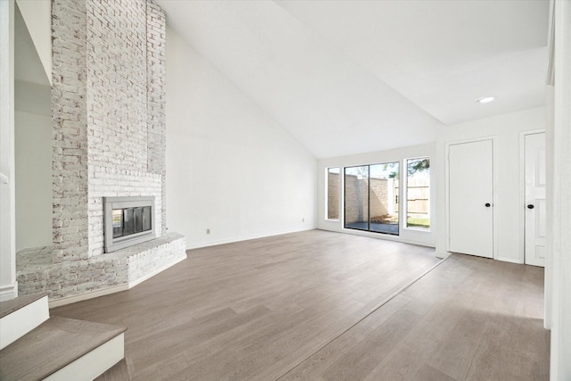 unfurnished living room featuring wood-type flooring, high vaulted ceiling, and a brick fireplace