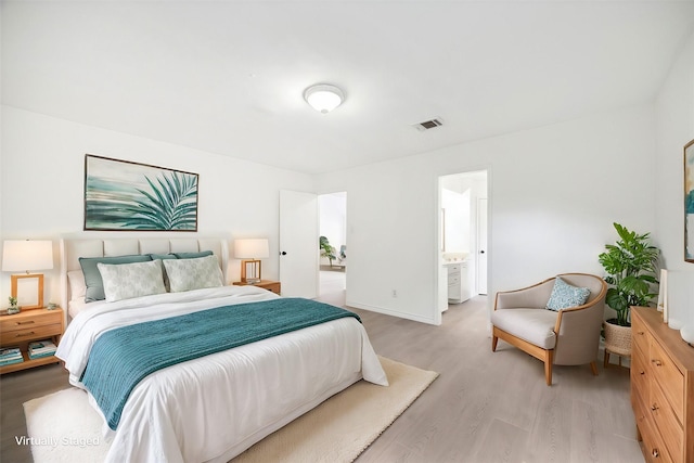 bedroom featuring ensuite bathroom and light hardwood / wood-style floors