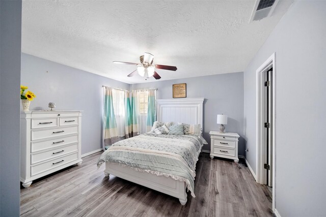 bedroom featuring ceiling fan, light hardwood / wood-style floors, and a textured ceiling