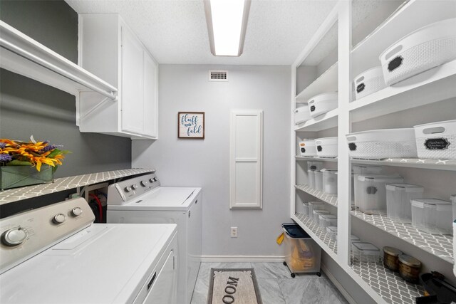 washroom featuring cabinets, a textured ceiling, and independent washer and dryer