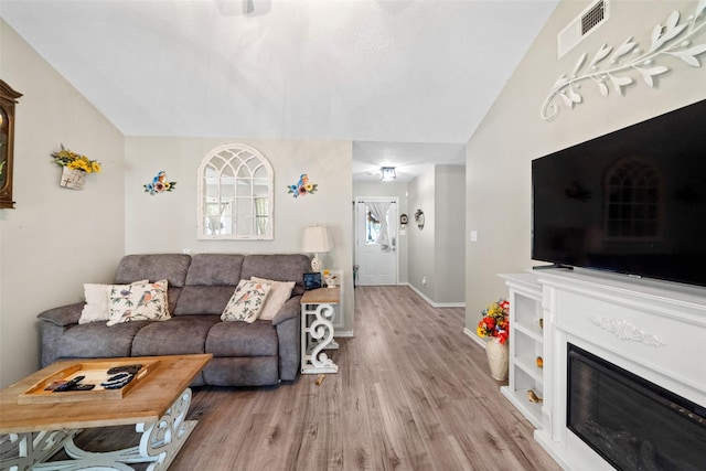 living room with light hardwood / wood-style flooring and vaulted ceiling