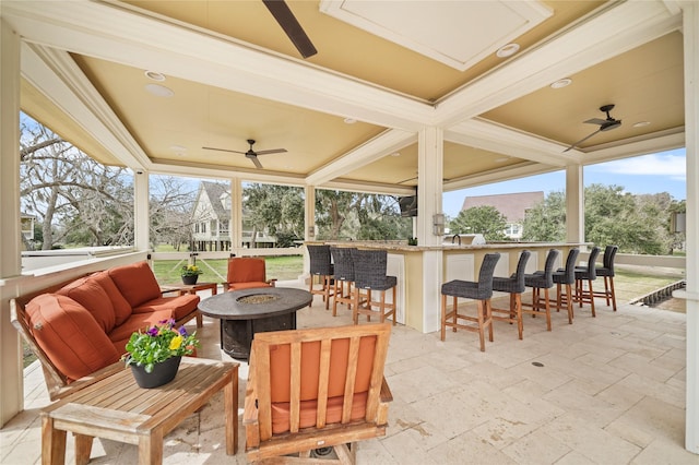 view of patio with an outdoor fire pit, ceiling fan, and exterior bar