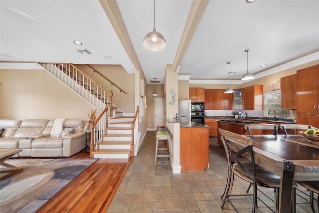 kitchen featuring crown molding, a kitchen bar, sink, and hanging light fixtures