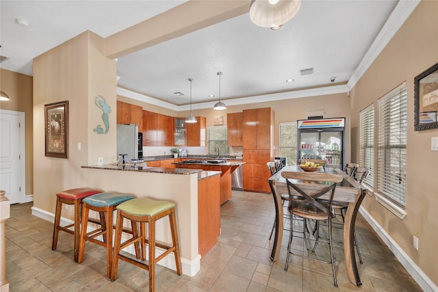 kitchen featuring white refrigerator, ornamental molding, a kitchen breakfast bar, kitchen peninsula, and pendant lighting