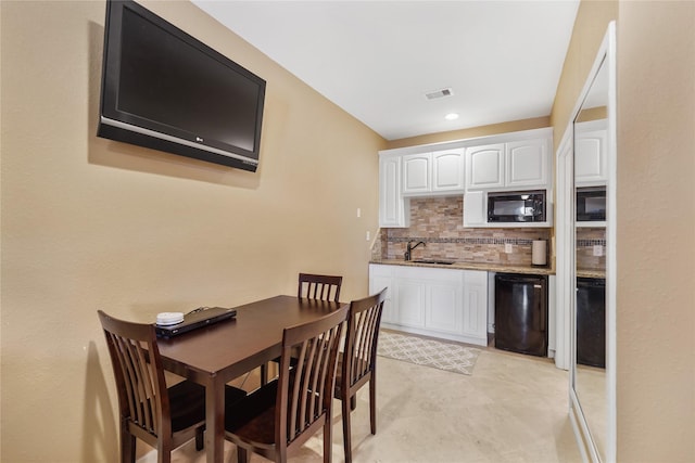 kitchen featuring sink, black appliances, white cabinets, decorative backsplash, and dark stone counters