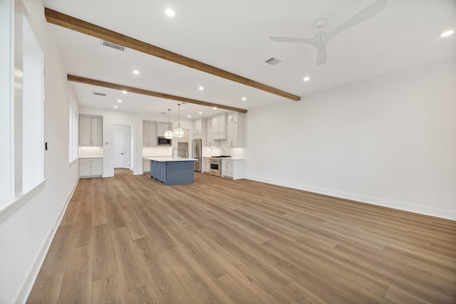 unfurnished living room featuring ceiling fan, light hardwood / wood-style floors, sink, and beamed ceiling