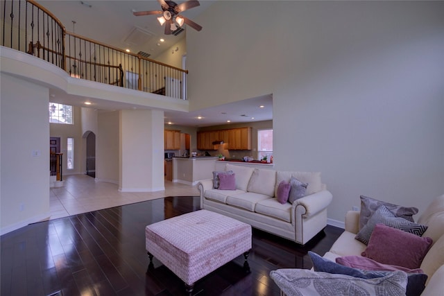 living room featuring a towering ceiling, ceiling fan, and plenty of natural light