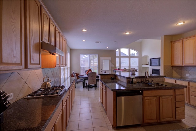 kitchen featuring kitchen peninsula, light tile patterned floors, decorative backsplash, appliances with stainless steel finishes, and sink