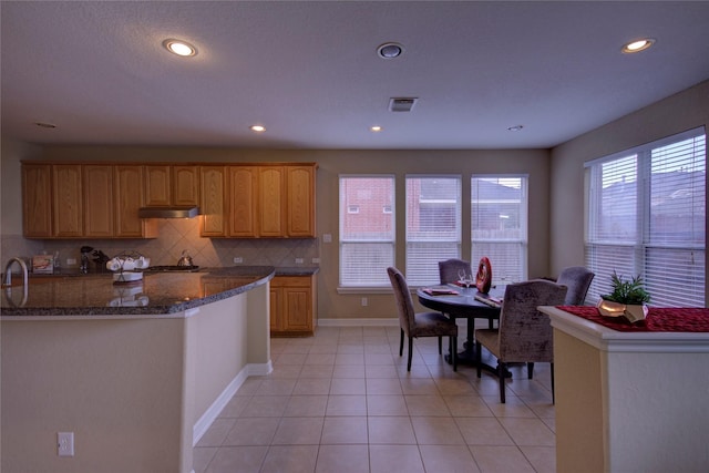 kitchen with dark stone counters, decorative backsplash, and light tile patterned floors