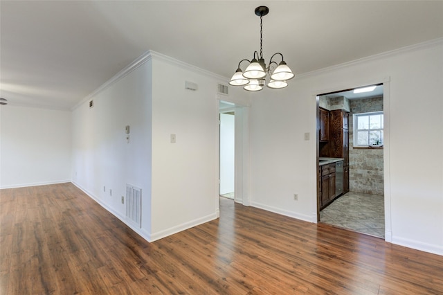 empty room featuring hardwood / wood-style flooring, an inviting chandelier, and crown molding