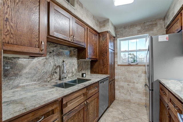 kitchen with light stone counters, sink, light tile patterned floors, and appliances with stainless steel finishes