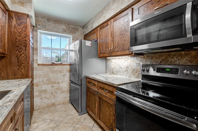 kitchen with decorative backsplash, light tile patterned flooring, light stone counters, and appliances with stainless steel finishes