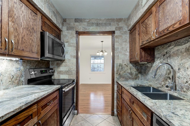 kitchen featuring a notable chandelier, light stone counters, sink, and appliances with stainless steel finishes