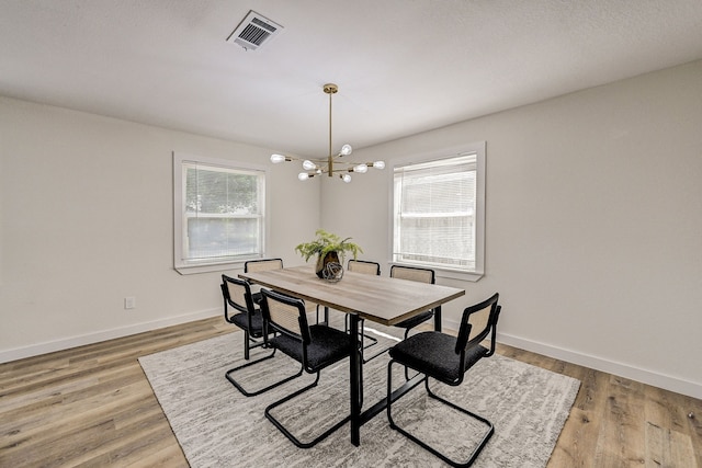 dining area with a wealth of natural light, hardwood / wood-style flooring, and a notable chandelier