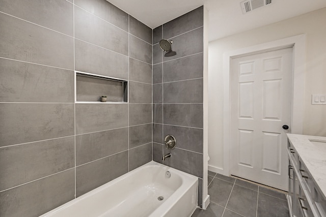 bathroom featuring tile patterned flooring, vanity, and tiled shower / bath