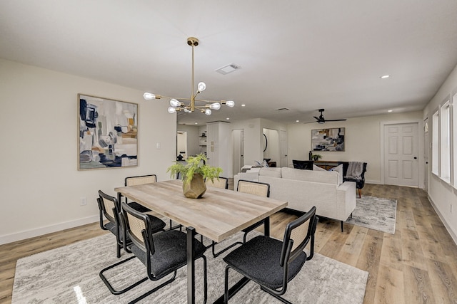 dining room featuring ceiling fan with notable chandelier and light hardwood / wood-style floors