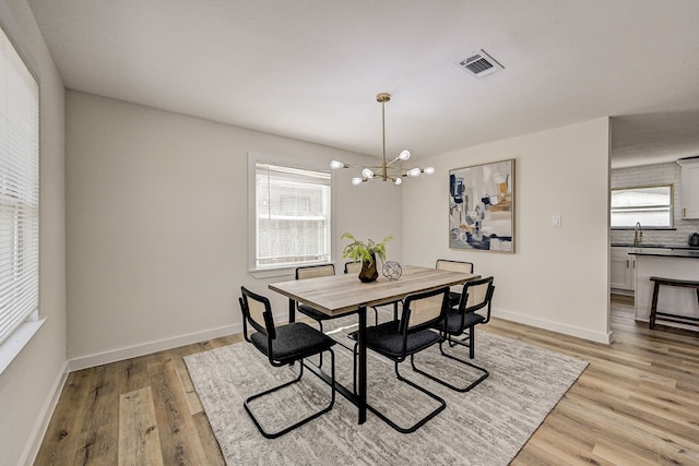 dining area with light hardwood / wood-style flooring and an inviting chandelier