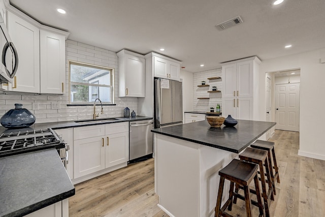 kitchen with white cabinets, appliances with stainless steel finishes, a kitchen island, and sink