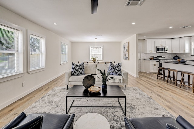 living room featuring plenty of natural light, light hardwood / wood-style floors, and an inviting chandelier