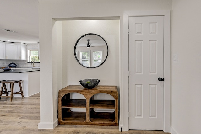 room details with decorative backsplash, hardwood / wood-style floors, and ceiling fan