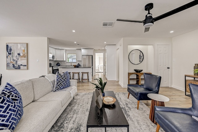 living room featuring ceiling fan and light hardwood / wood-style flooring