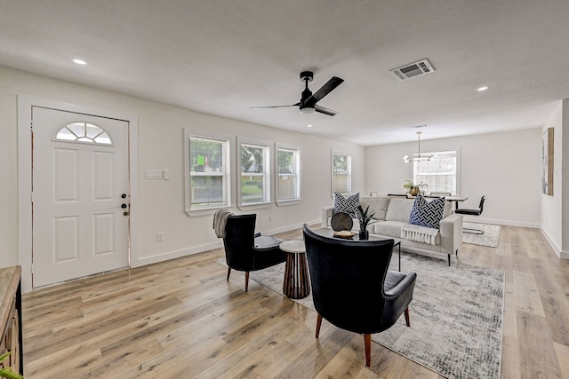 living room featuring light hardwood / wood-style floors and ceiling fan with notable chandelier