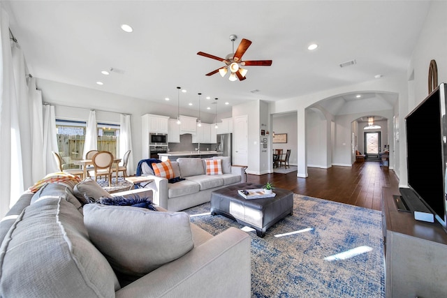 living room featuring ceiling fan and dark hardwood / wood-style floors