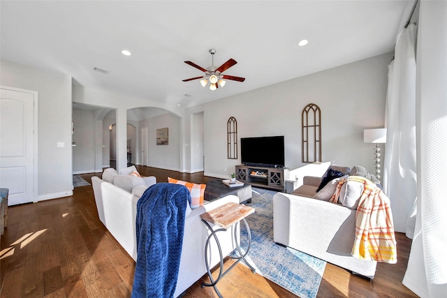 living room featuring ceiling fan and dark wood-type flooring