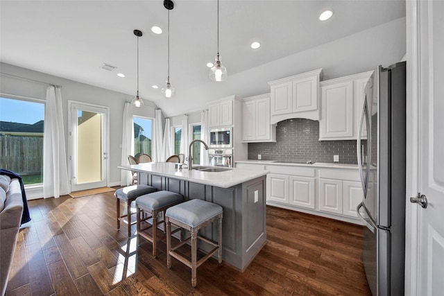 kitchen featuring pendant lighting, a breakfast bar, white cabinets, a center island with sink, and appliances with stainless steel finishes