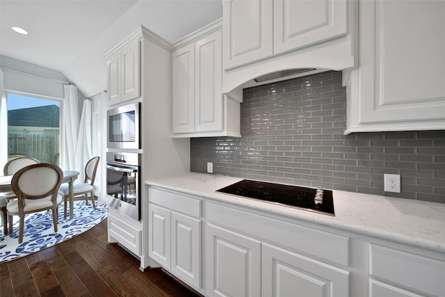 kitchen with black electric stovetop, white cabinetry, oven, and tasteful backsplash