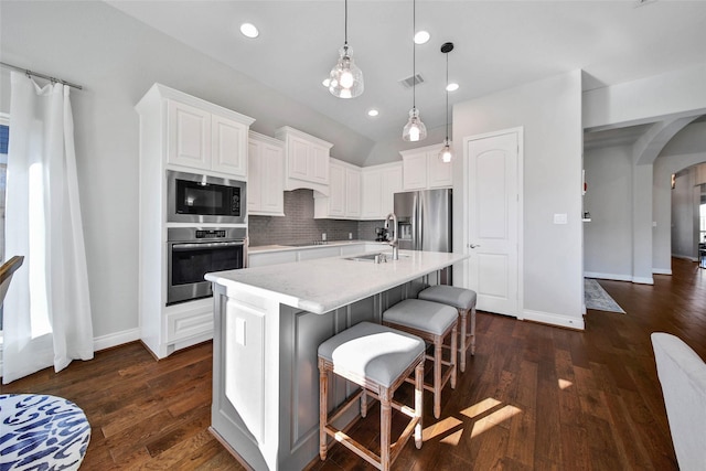 kitchen with a kitchen bar, appliances with stainless steel finishes, sink, white cabinets, and an island with sink