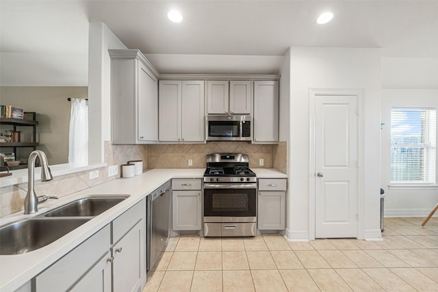 kitchen featuring sink, gray cabinets, appliances with stainless steel finishes, tasteful backsplash, and light tile patterned flooring