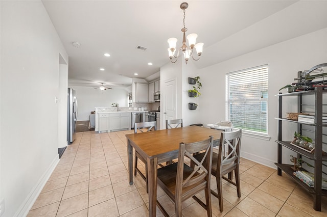 dining space featuring sink, light tile patterned flooring, and ceiling fan with notable chandelier