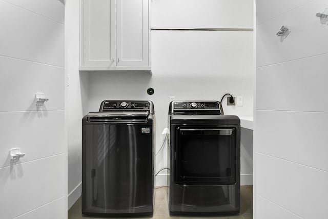 clothes washing area featuring cabinets and washer and dryer