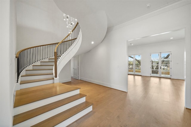 stairs with hardwood / wood-style flooring, crown molding, and a chandelier