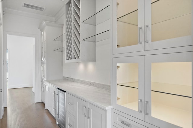 bar with white cabinets, wine cooler, light stone counters, and crown molding