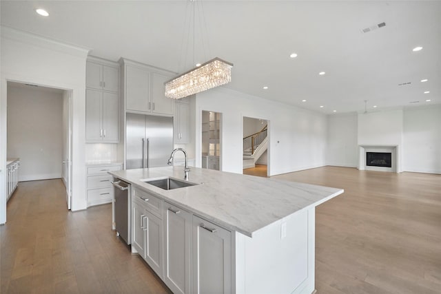 kitchen with pendant lighting, sink, an island with sink, and stainless steel appliances