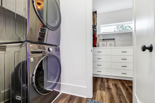 clothes washing area featuring dark hardwood / wood-style flooring and stacked washing maching and dryer