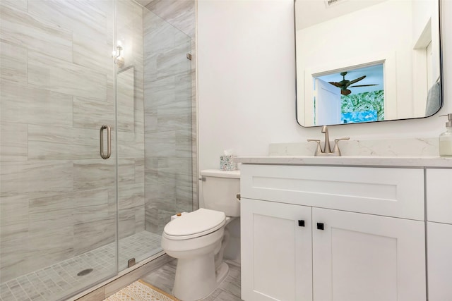 bathroom featuring vanity, toilet, an enclosed shower, and ceiling fan