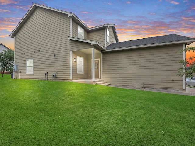 back house at dusk with a lawn