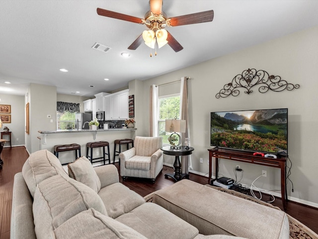 living room featuring ceiling fan and dark hardwood / wood-style flooring