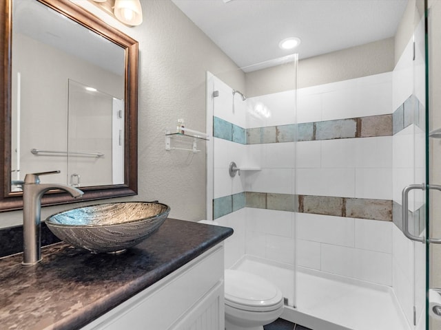 bathroom featuring a shower with door, vanity, and toilet