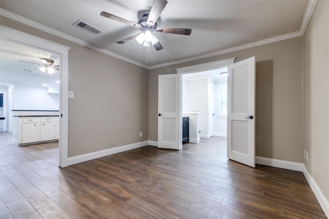 unfurnished bedroom featuring ceiling fan, wood-type flooring, crown molding, and connected bathroom