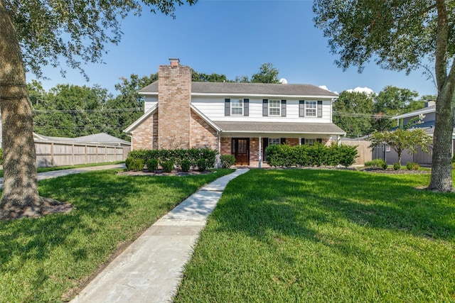 view of front of property featuring brick siding, a chimney, fence, and a front yard