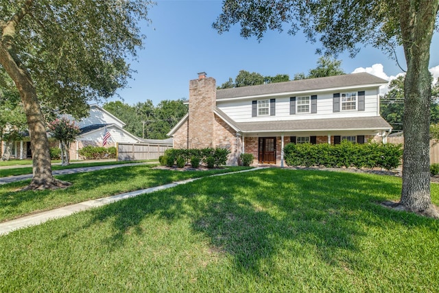 traditional-style house with a chimney, fence, a front lawn, and brick siding