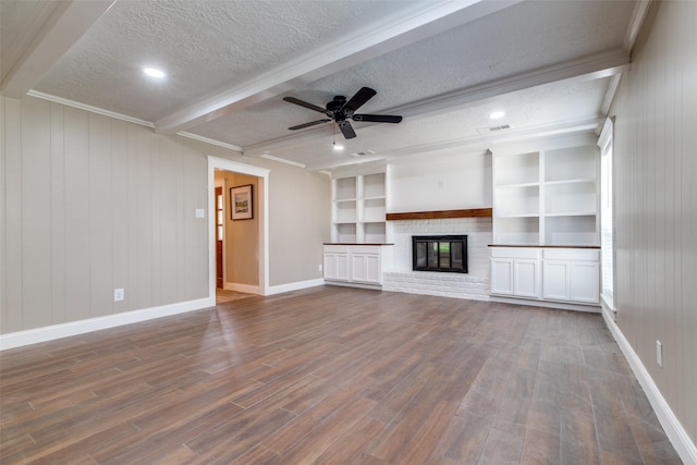 unfurnished living room featuring beam ceiling, ceiling fan, a brick fireplace, built in features, and a textured ceiling