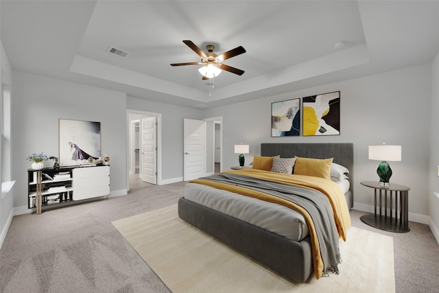 bedroom featuring light carpet, a raised ceiling, and ceiling fan